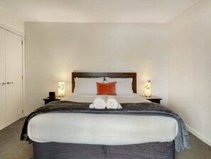 A hotel room with a large bed, two bedside tables, and a door. - Cosy Alpine Lakeview Suite for Couples (Queenstown)