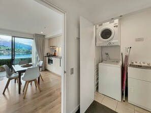 Uma cozinha moderna com máquina de lavar e secadora embutidas, área de refeições com vista para um lago e uma mesa de jantar separada.