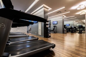 A gym with treadmills, exercise equipment, and a TV screen. - Central Spacious Yorkville Suite (Toronto)