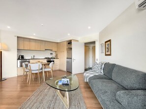 A modern apartment with a dining area, kitchen, and living room. - Tranquil 1 Bed Corner Suite, Lake & Mountain Views (Queenstown)