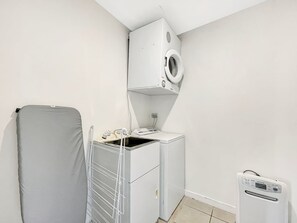A compact laundry room with a washing machine, dryer, and a small heater. - Tranquil 1 Bed Corner Suite, Lake & Mountain Views (Queenstown)