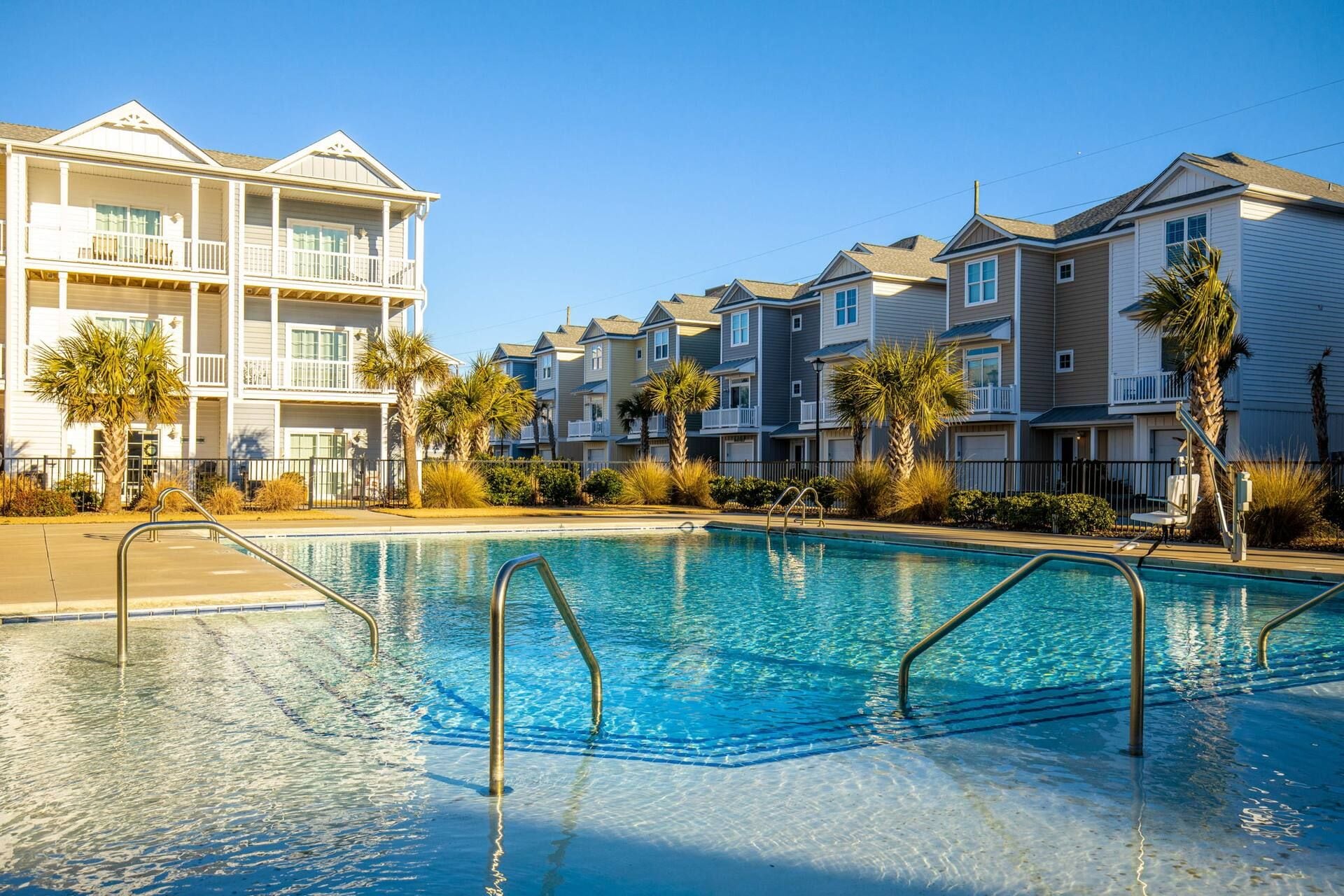 A swimming pool with clear blue water, surrounded by multi-story residential buildings with balconies.