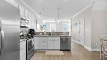 A modern kitchen with stainless steel appliances, white cabinetry, and a central island.