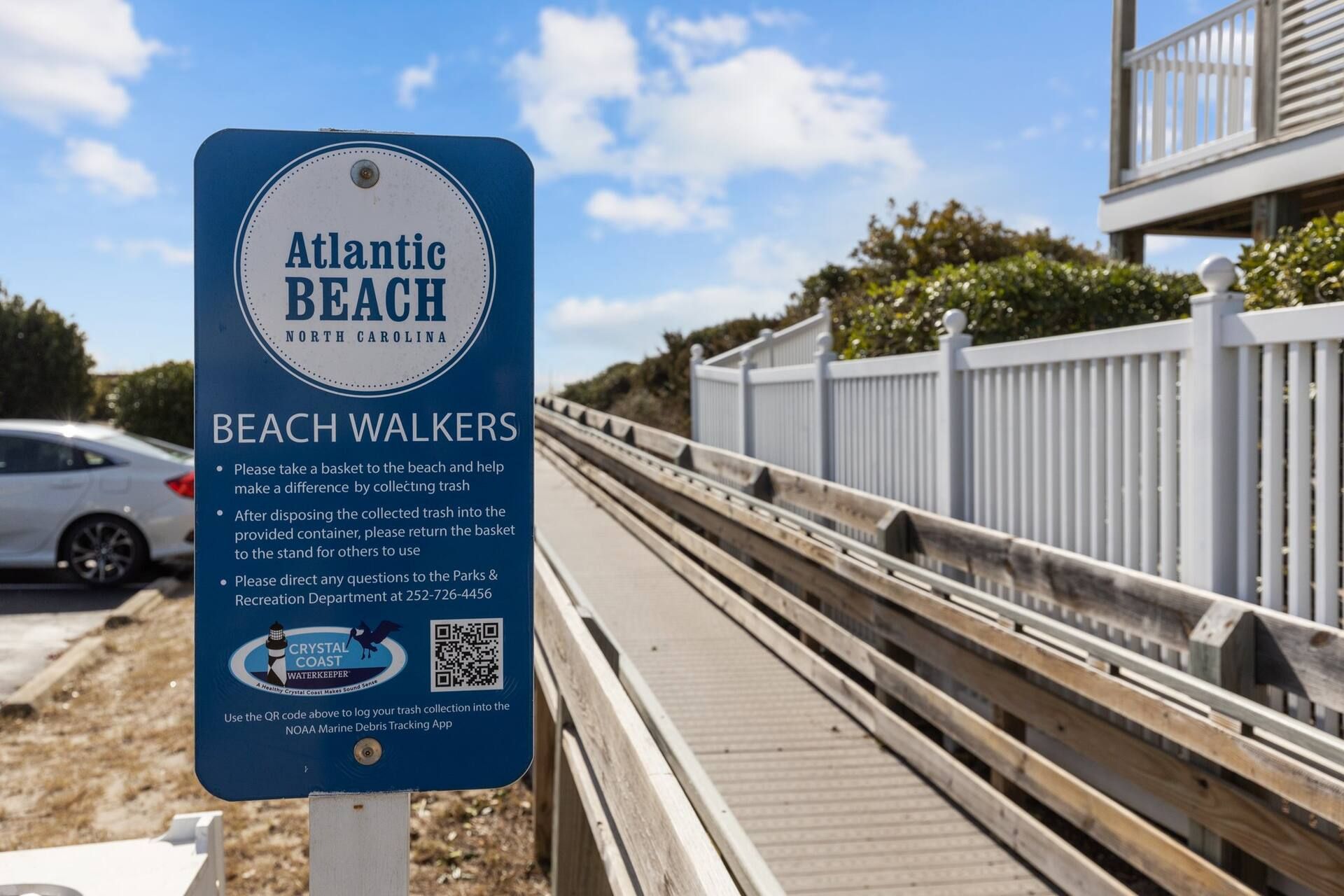 A sign for Atlantic Beach North Carolina, instructing beach walkers to collect trash and return it to the stand.