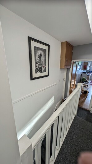 Ein Flur mit weißer Geländer, einem gerahmten Bild an der Wand und einer Küchenzeile im Hintergrund.