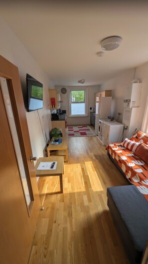 A compact living space with a kitchenette, a dining area, and a sofa. - Southsea 3-Bed Flat | Spacious & Comfortable (Portsmouth)