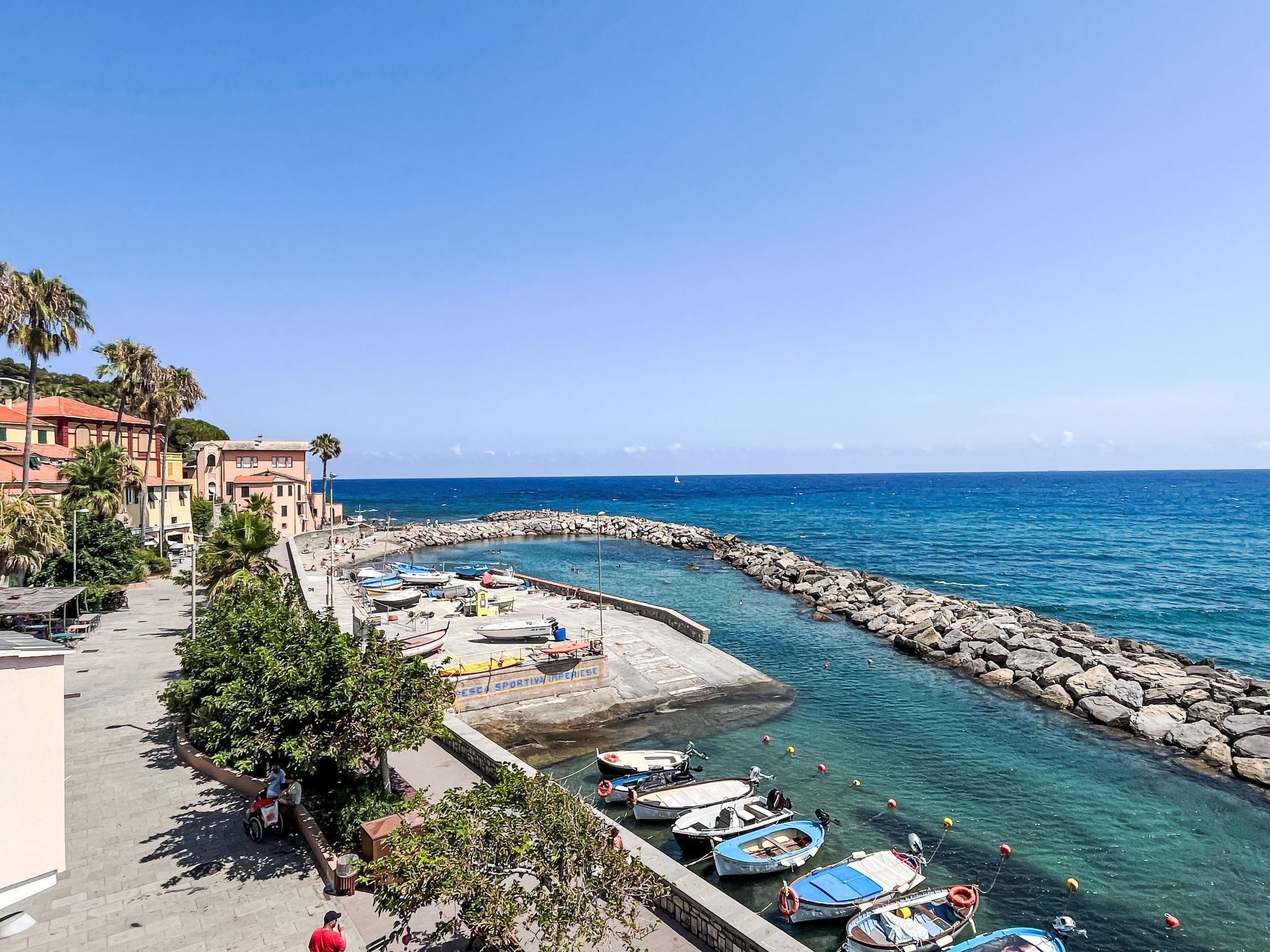 A coastal town with a marina, boats, and buildings along the waterfront.