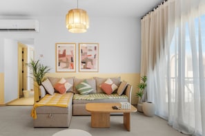 A modern living room with a sofa, a coffee table, and two framed abstract paintings on the wall.