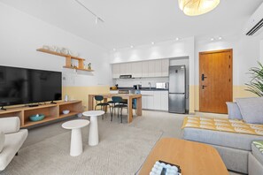 Una sala de estar moderna con una televisión de pantalla plana, una mesa de centro y un sofá.