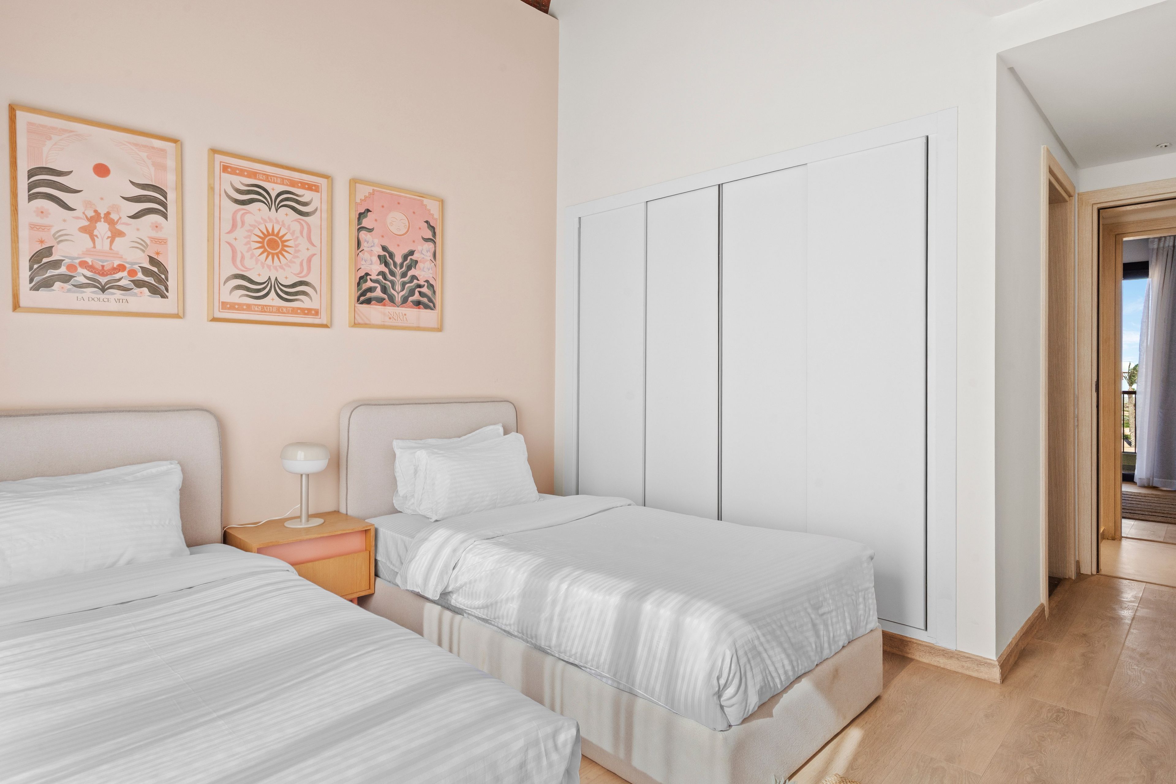 A bedroom with two beds, a nightstand, and a wardrobe.
