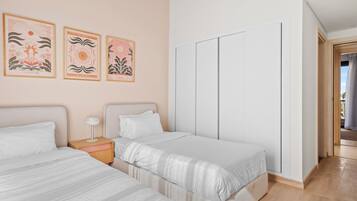 A bedroom with two beds, a nightstand, and a wardrobe.
