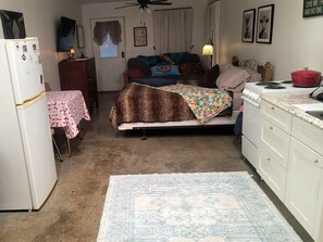 Ein gemütliches Schlafzimmer mit Bett, kleinem Tisch, Kühlschrank, Herd und einem gemusterten Teppich.