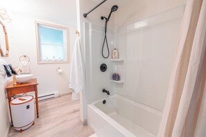 Un baño con bañera, lavamanos, inodoro y ventana.