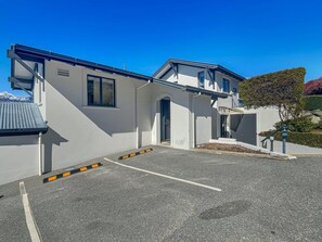 A modern building with a parking area in front. - Peaceful Alpine Villa, Lake Views, Sleeps 6 (Queenstown)