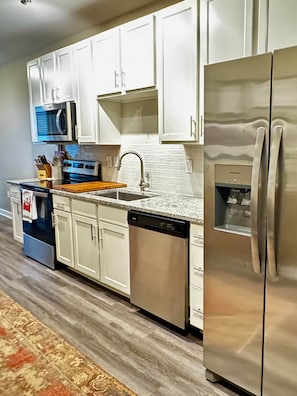 A modern kitchen with white cabinets, stainless steel appliances, and a granite countertop. - Pet Friendly Downtown Athens Condo W/ Parking (Athens)