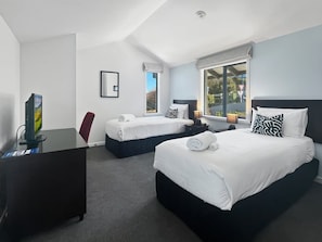 Ein Hotelzimmer mit zwei Betten, einem Schreibtisch und einem Fenster mit Blick.