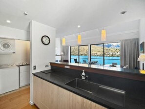 Eine moderne Küche mit einer schwarzen Arbeitsplatte, einem Spülbecken und einem Fenster mit Blick auf eine schöne Landschaft.