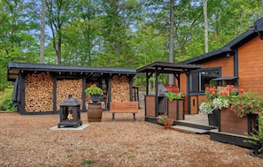 Eine Holzhütte mit Feuerstelle, Sitzgelegenheit und Außengrillküche.
