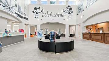 A spacious lobby with a central reception desk, a large welcome sign, and a high ceiling with skylights.
