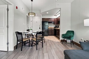 A modern kitchen with dark wooden cabinets, a black refrigerator, and a dining area with a white table and black chairs.