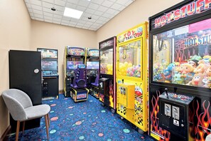 A room with arcade games, a chair, and a vending machine.
