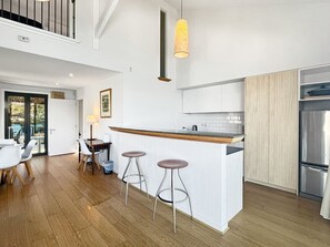 A modern kitchen with a central island, bar stools, and a stainless steel refrigerator. - Alpine Lakeview Villa, 3 Bed, Queenstown (Queenstown)