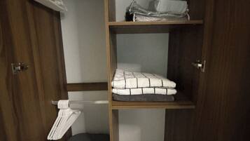 Un armario de madera con varios estantes, una barra para colgar ropa y un cesto de ropa.