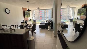 A modern kitchen with a dining area, large windows, and a view of a residential building.
