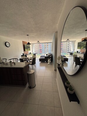 A modern kitchen with a dining area, large windows, and a view of a residential building. - 3-bedroom / 2 bathroom apartment in superb San Marcos with AC, close to airport! (San Marcos)