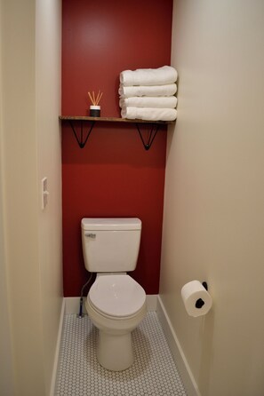 Ein kleines Badezimmer mit Toilette, einem Handtuchregal und einem Toilettenpapierhalter.