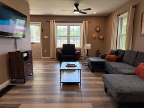 A living room with a TV, a sofa, a coffee table, and a fireplace.