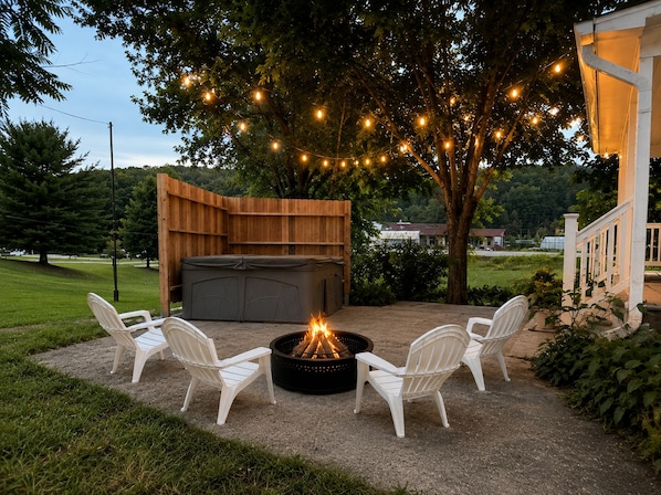 An outdoor patio with a fire pit, seating, and string lights.