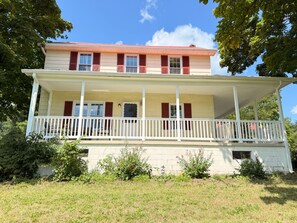 A two-story house with a front porch and a small garden area.