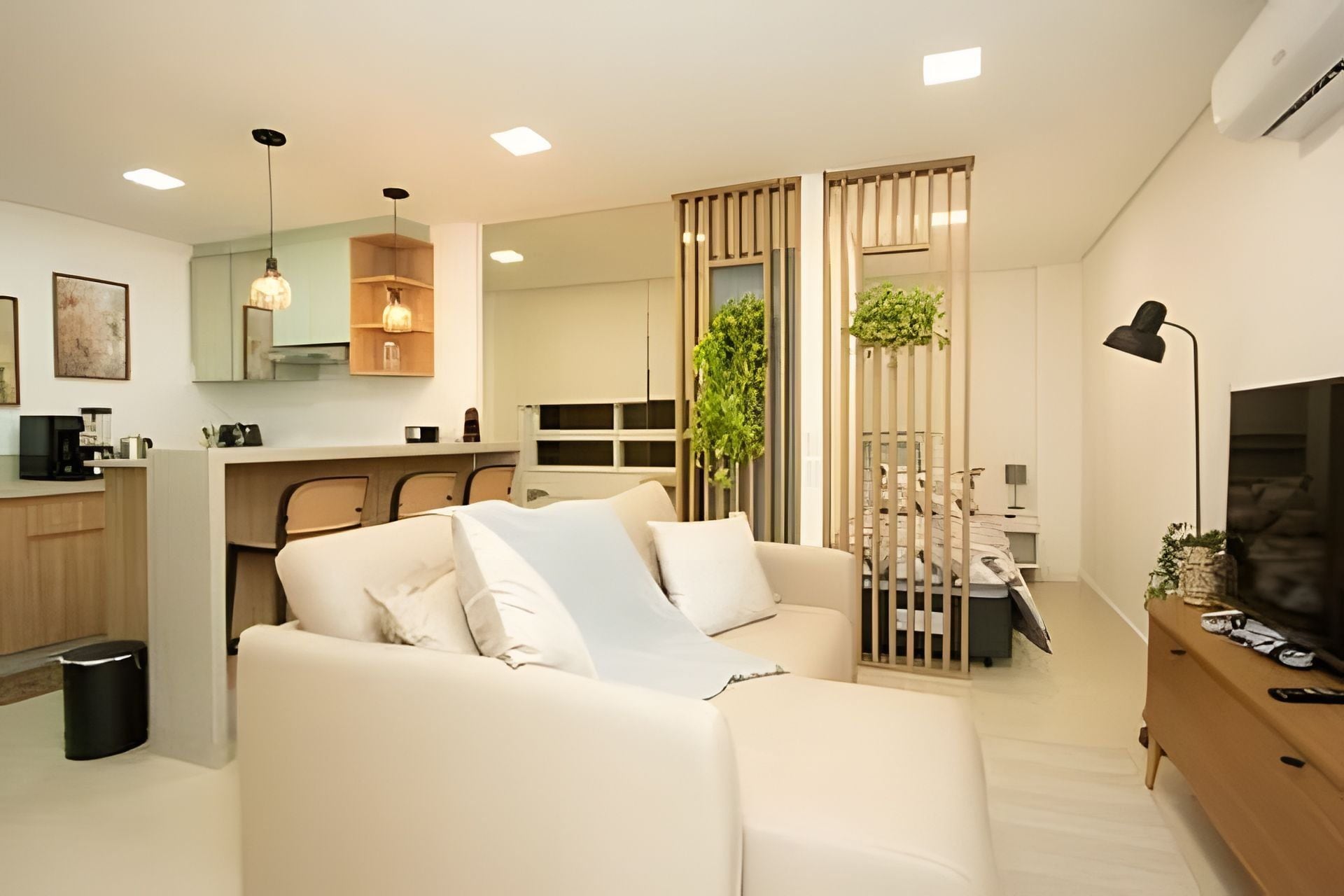 Una sala de estar moderna con un sofá, una televisión y una cocina al fondo.