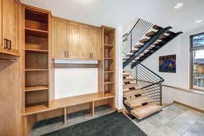 Un intérieur moderne avec des étagères en bois, un escalier doté de rampes en métal et une vue par la fenêtre.