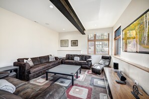 Un salon moderne avec un canapé d’angle, une table basse et un téléviseur.