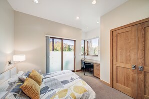 Quarto com cama, escrivaninha e porta de correr para uma varanda.