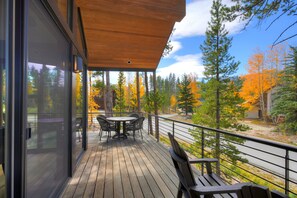 A wooden deck with a table and chairs, overlooking a forest with autumn foliage. - NEW Cloud 9 Cabin in Warrior's Mark near Peak 9 & 10. Amazing Views & Mtn Access! (Breckenridge)