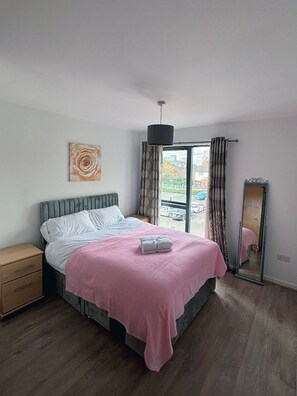 A bedroom with a bed, bedside table, and a window with curtains. - 2BR Manchester Apartment near Old Trafford (Manchester)