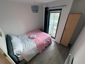 Een slaapkamer met een bed, nachtkastje, raam met uitzicht en een radiator.