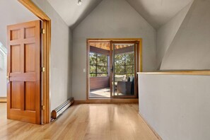 Une pièce dotée d’une porte en bois, d’une porte-fenêtre coulissante donnant sur un espace extérieur et d’un plafond en pente.