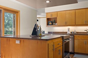 A modern kitchen with wooden cabinets, a built-in oven, and a window providing natural light. - Elite Lakefront | Sunroom | UpNorth Family Haven (Brainerd)