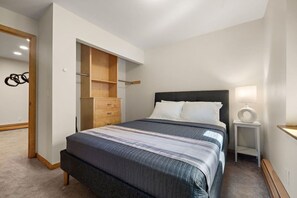 A bedroom with a bed, a nightstand, a lamp, a wardrobe, and a mirror. - Elite Lakefront | Sunroom | UpNorth Family Haven (Brainerd)