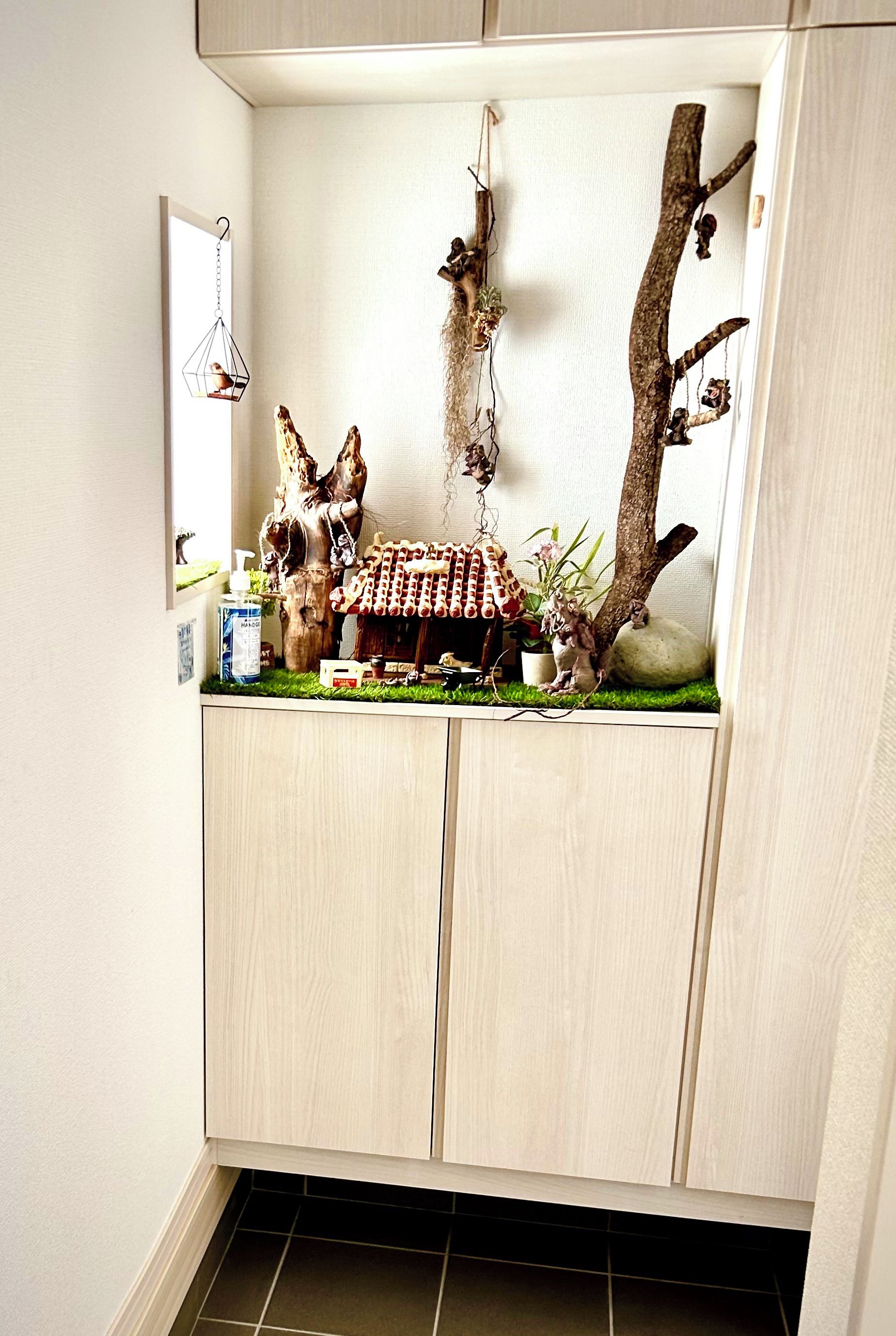 A room with a built-in cabinet featuring a miniature forest scene with trees, branches, and a small house.