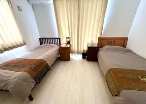 A hotel room with two beds, a nightstand, a lamp, and a window with curtains. - Just a 2-minute drive to the ocean! A whole-house rental located right near Hanajo no Sato Beach (八重瀬町)