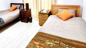 A hotel room with two beds, a wooden nightstand, a desk, and a trash bin.