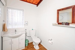 Un baño con lavamanos, inodoro y espejo blancos.