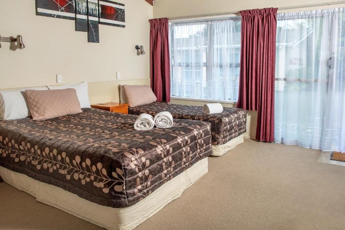 Habitación de hotel con dos camas, una ventana con cortinas y una obra de arte en la pared.