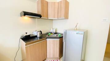 Eine kleine Küche mit Holzausstattung, inklusive Backofen, Spüle und Kühlschrank.