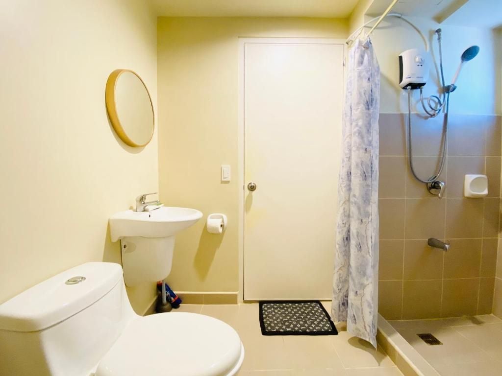 A bathroom with a toilet, sink, shower, and a door.